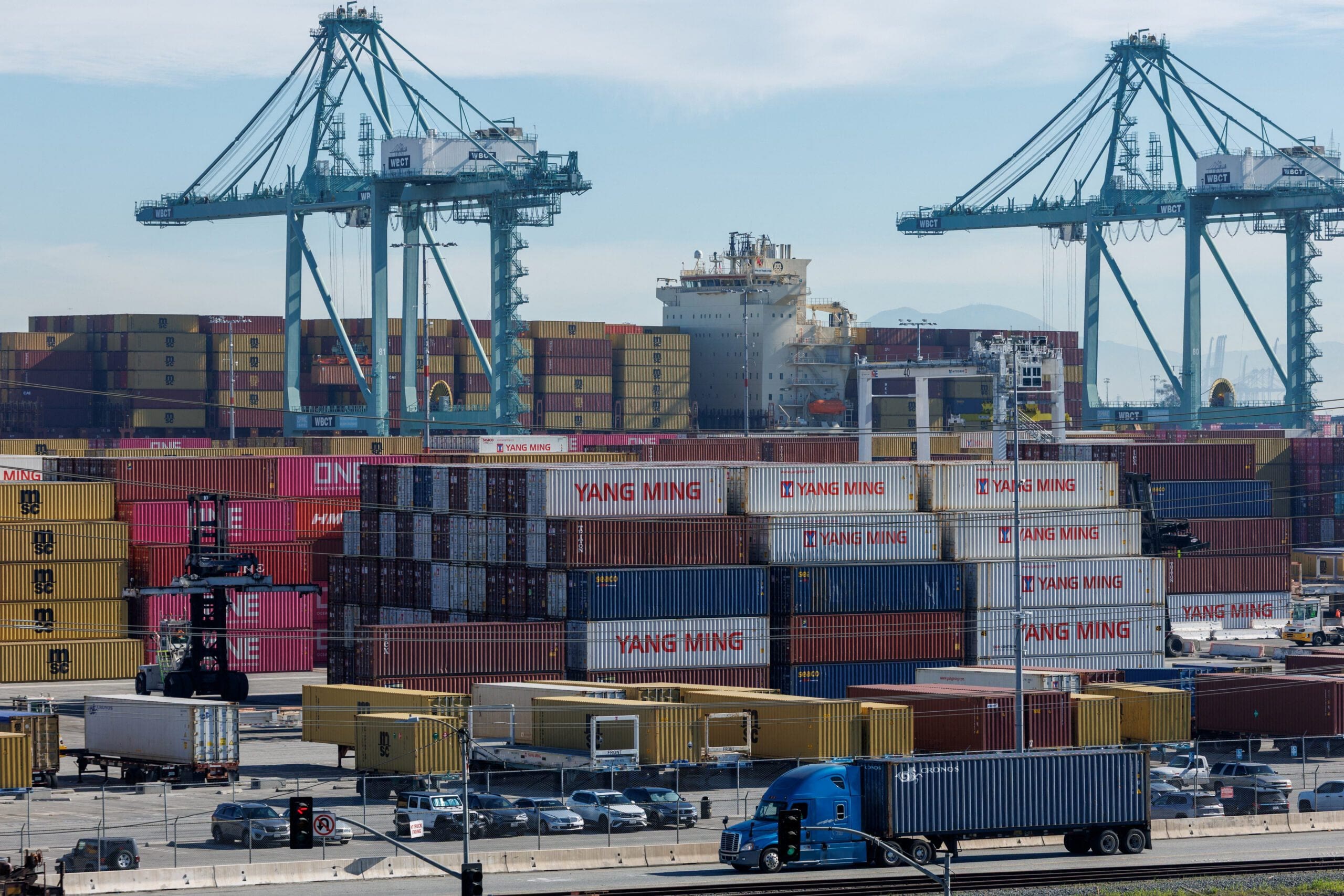 Shipping containers at a port representing the US tariff war and global trade impact